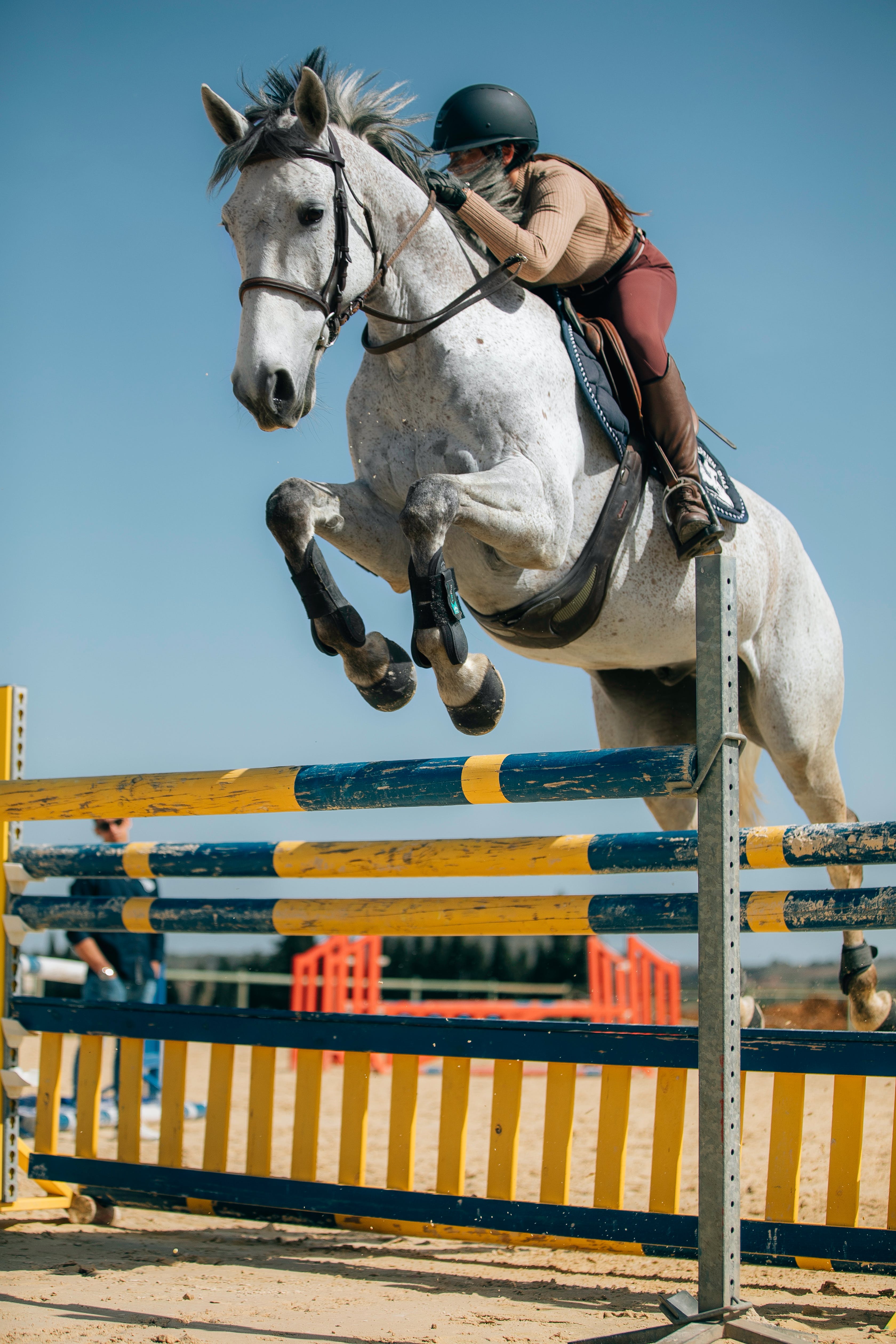 Picture of a horse and rider jumping over an obstacle.