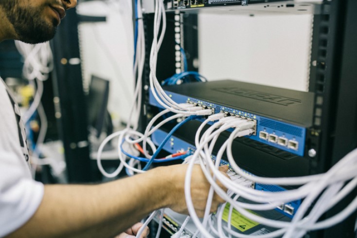 A man plugging in network cables